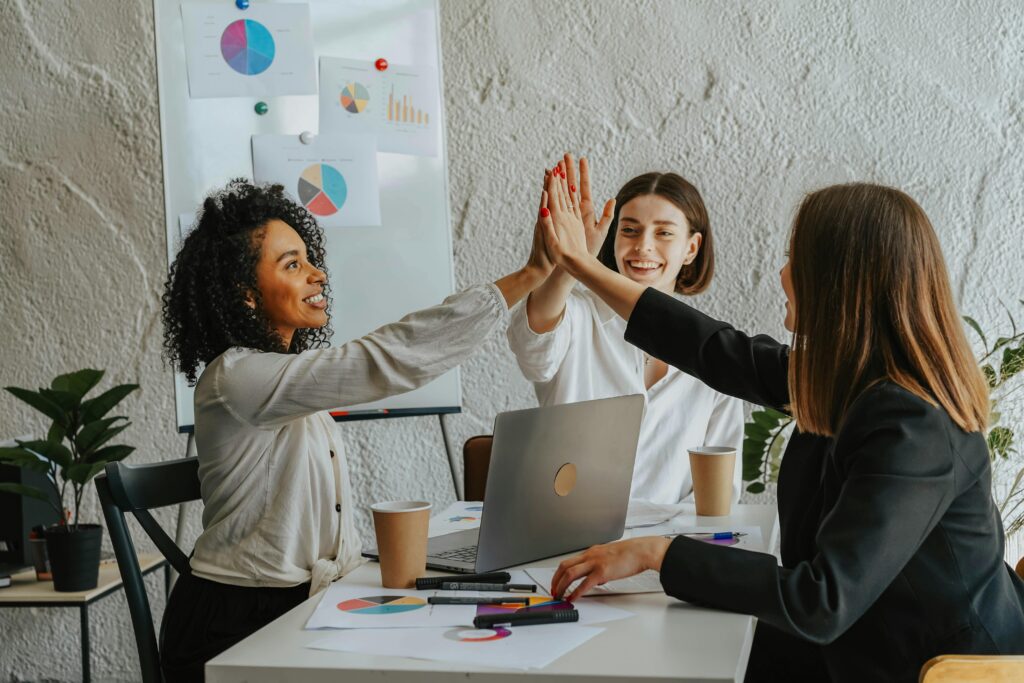 Three businesswomen in office having a high-five during a successful meeting.